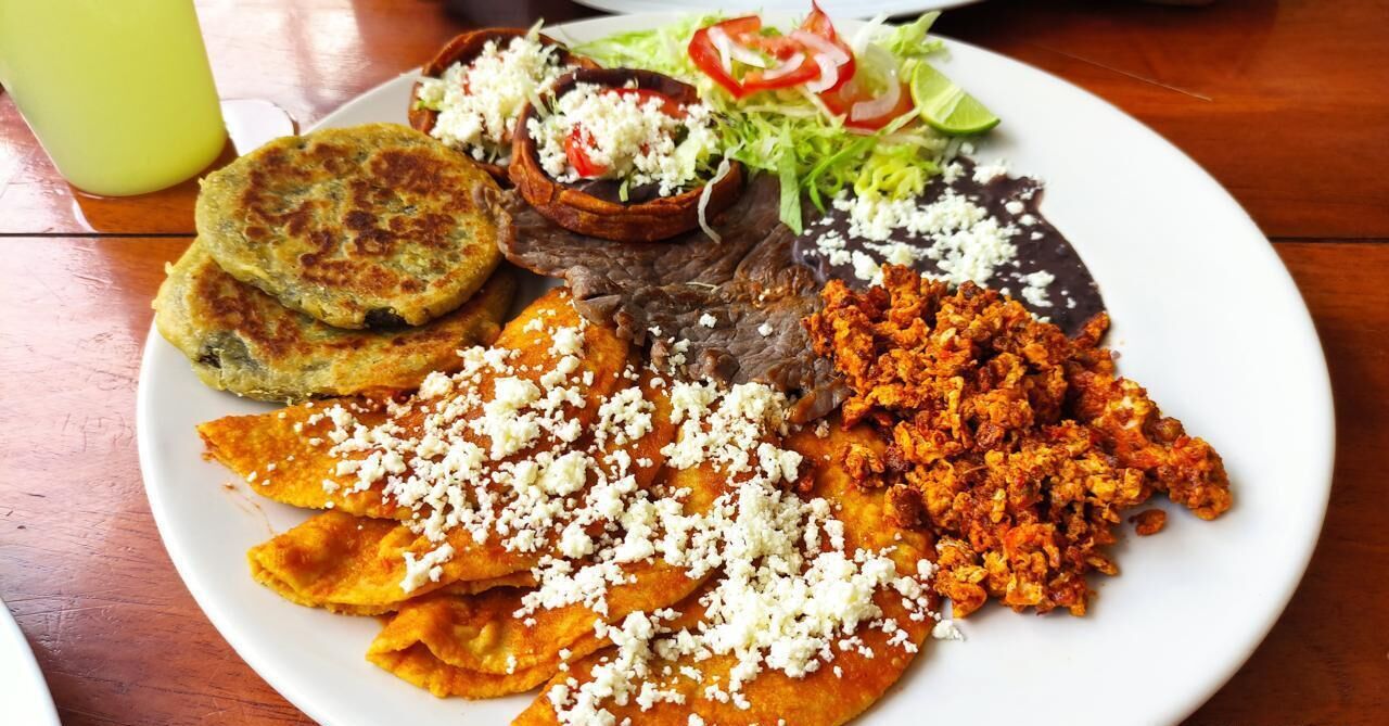 Lautasella on erilaisia ruokia, kuten juustolla päällystettyjä tortilloja, liharuoka ja salaatti.