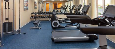 A gym with treadmills, dumbbells, and weight machines.