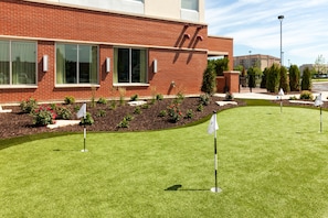 A modern building with large windows and a well-maintained lawn with a flag. - Hyatt Place Chicago Midway Airport (Chicago)