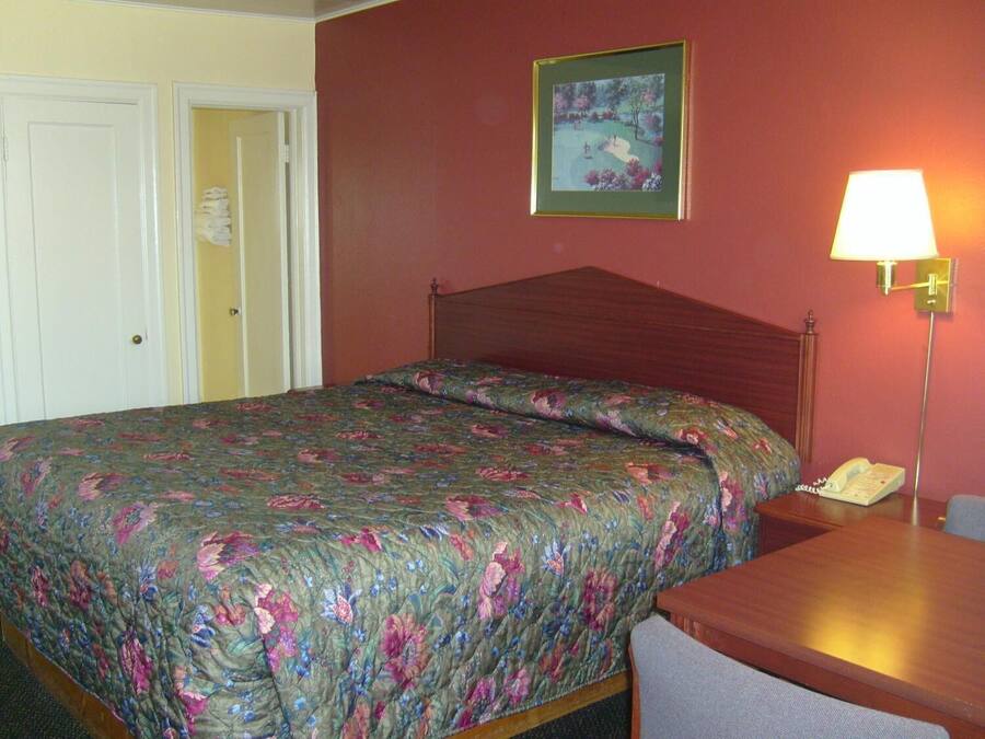 Een hotelkamer met een bed, een nachtkastje, een lamp en een schilderij aan de muur.