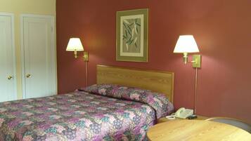 A hotel room with a bed, two bedside lamps, a round wooden table, and a telephone.