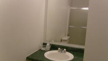 A bathroom with a white sink, green countertop, and a mirror above it.