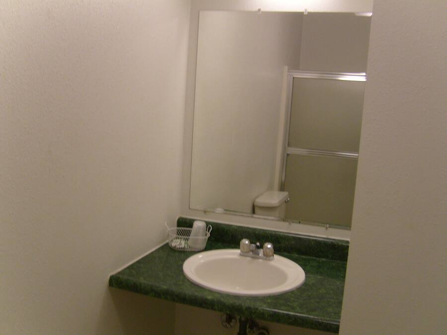 A bathroom with a white sink, green countertop, and a mirror above it.