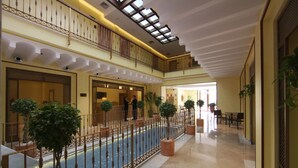A spacious indoor area with a central water feature, multiple levels with balconies, and potted plants. - Hotel Casa Consistorial (Fuengirola)