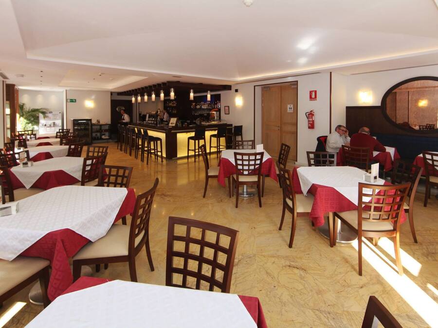 A restaurant with multiple tables and chairs, a bar area, and a fire extinguisher on the wall.