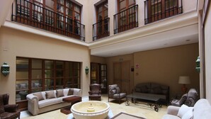 A spacious lobby with a high ceiling, multiple seating areas, and a central decorative fountain. - Hotel Casa Consistorial (Fuengirola)