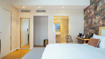 Een moderne hotelkamer met een groot bed, een badkamer met douche en een zithoek met tafel en stoelen.