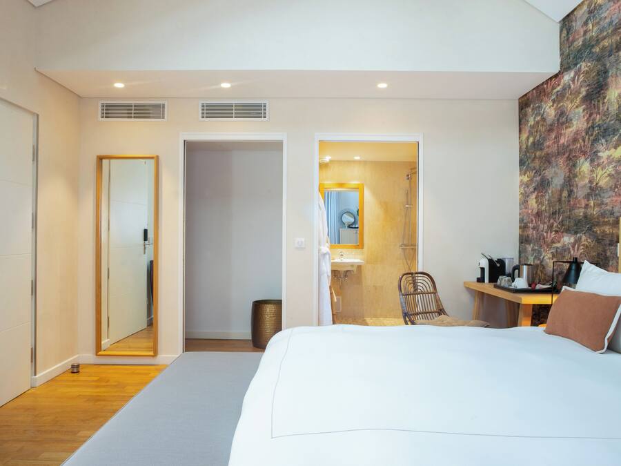 Een moderne hotelkamer met een groot bed, een badkamer met douche en een zithoek met tafel en stoelen.