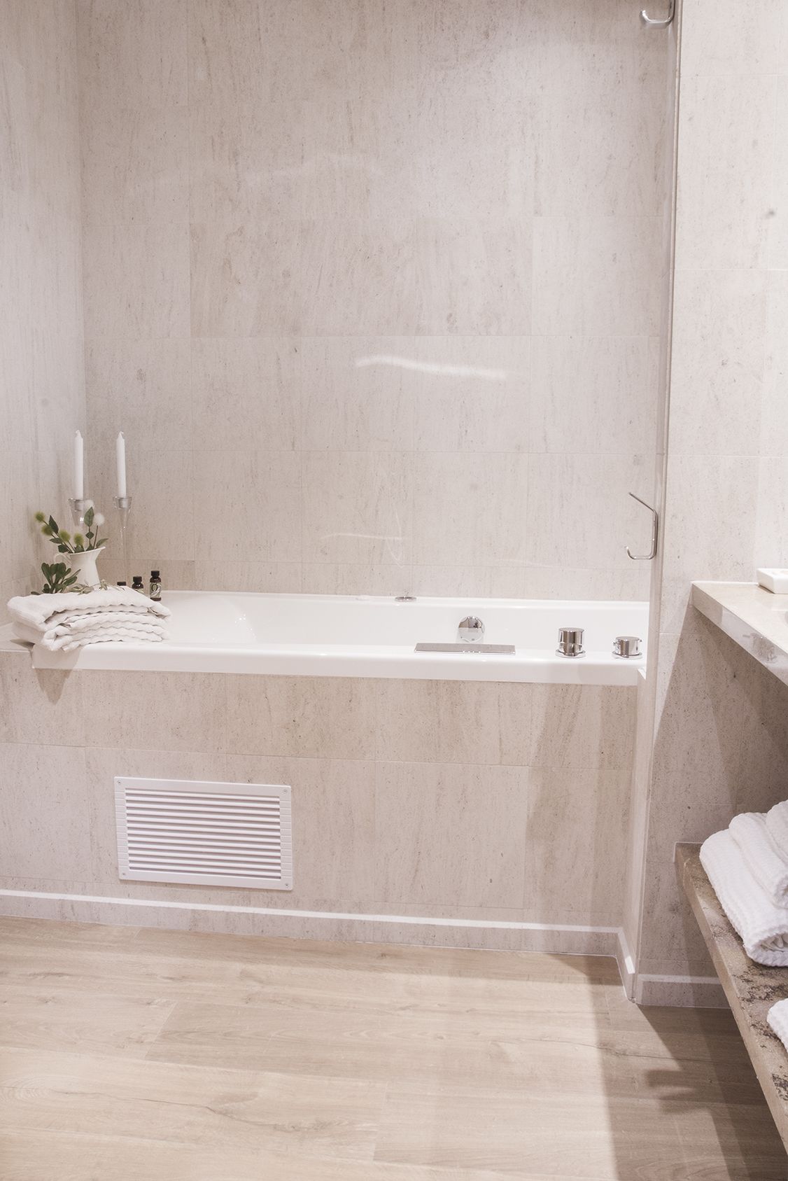 A modern bathroom with a freestanding bathtub, a towel rack, and a small shelf with toiletries.