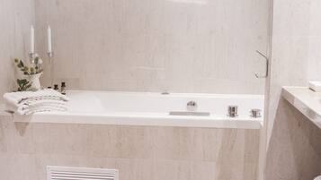 A modern bathroom with a freestanding bathtub, a towel rack, and a small shelf with toiletries.