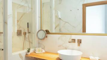 A modern bathroom with a large mirror, a round sink, and a shower area.