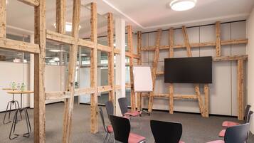 Un salón de conferencias de diseño moderno, con vigas de madera a la vista, un televisor de pantalla plana grande y varias sillas.
