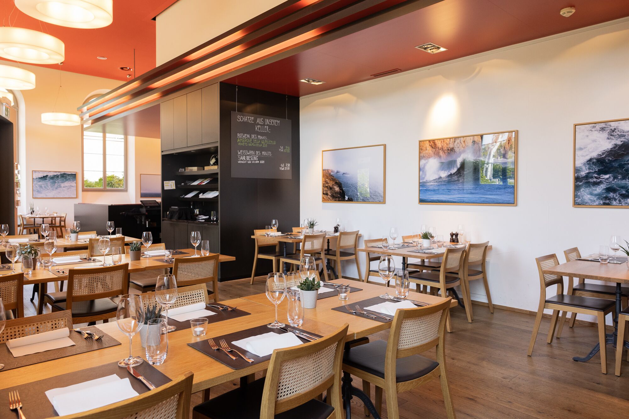 Un restaurant doté de nombreuses tables, de chaises et de luminaires suspendus.