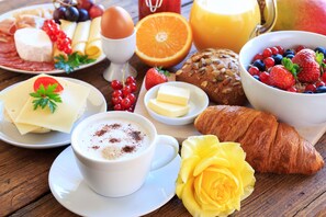 A breakfast setting with various food items including cheese, eggs, bread, and fruits.