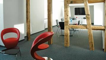 Un espace de bureau moderne avec des poutres en bois apparentes, des chaises rouges et une table de conférence.