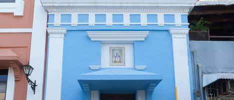 A building with a blue facade, a cross, and a door.