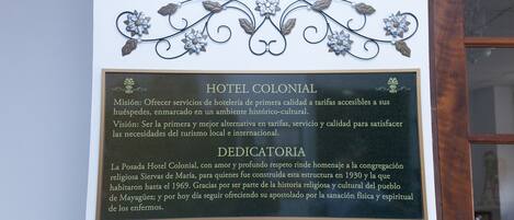 A plaque with the text "HOTEL COLONIAL" and "DEDICATORIA" on a wall.