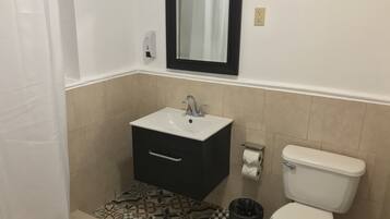 Un baño con lavabo, espejo, inodoro y baldosas de suelo estampadas.