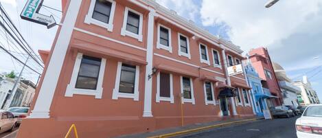 Un edificio rosa con múltiples ventanas y un letrero que indica un hotel.