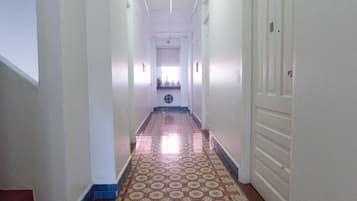 A long, narrow hallway with patterned floor tiles, white walls, and a ceiling light.