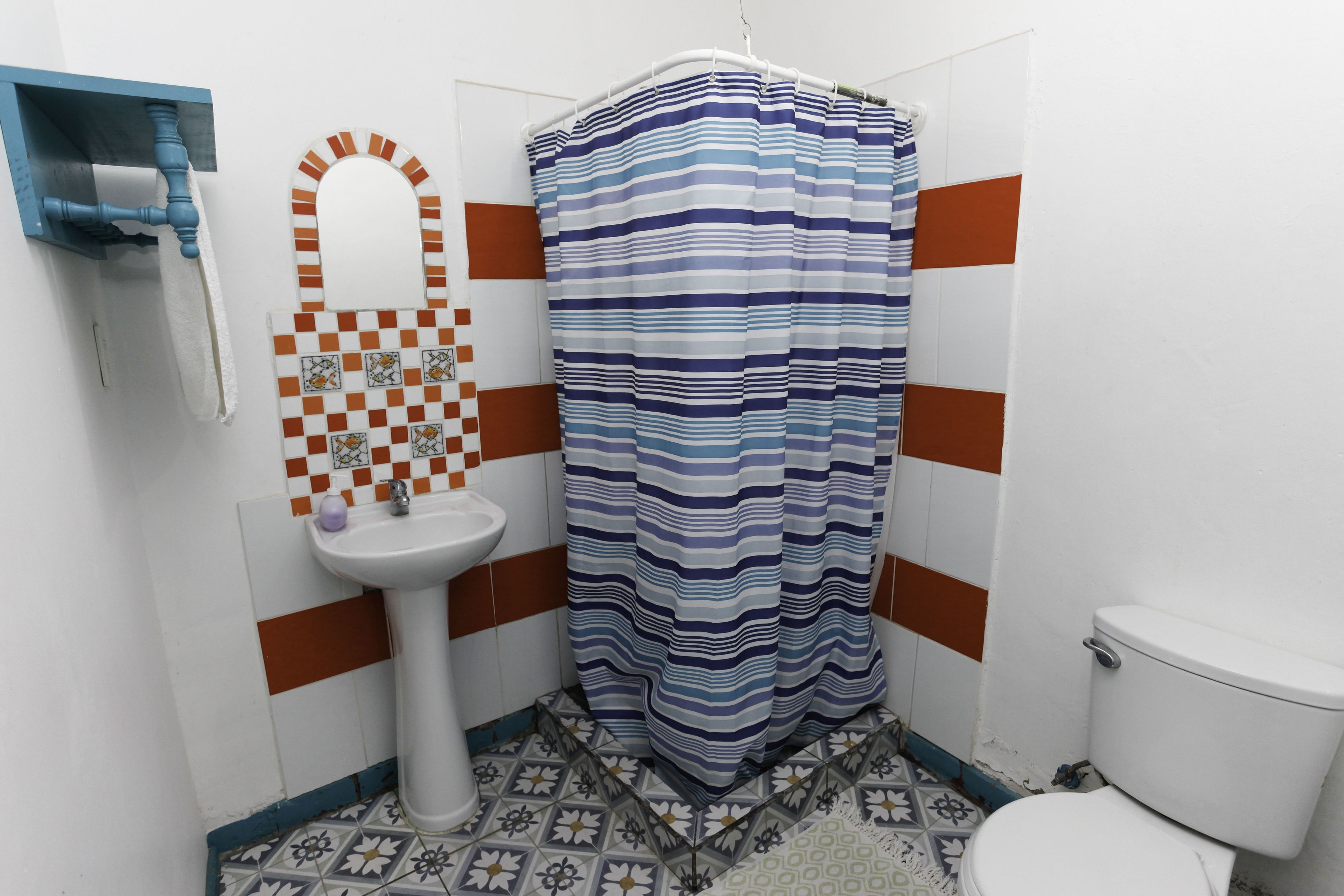 A bathroom with a striped shower curtain, a pedestal sink, and a toilet.