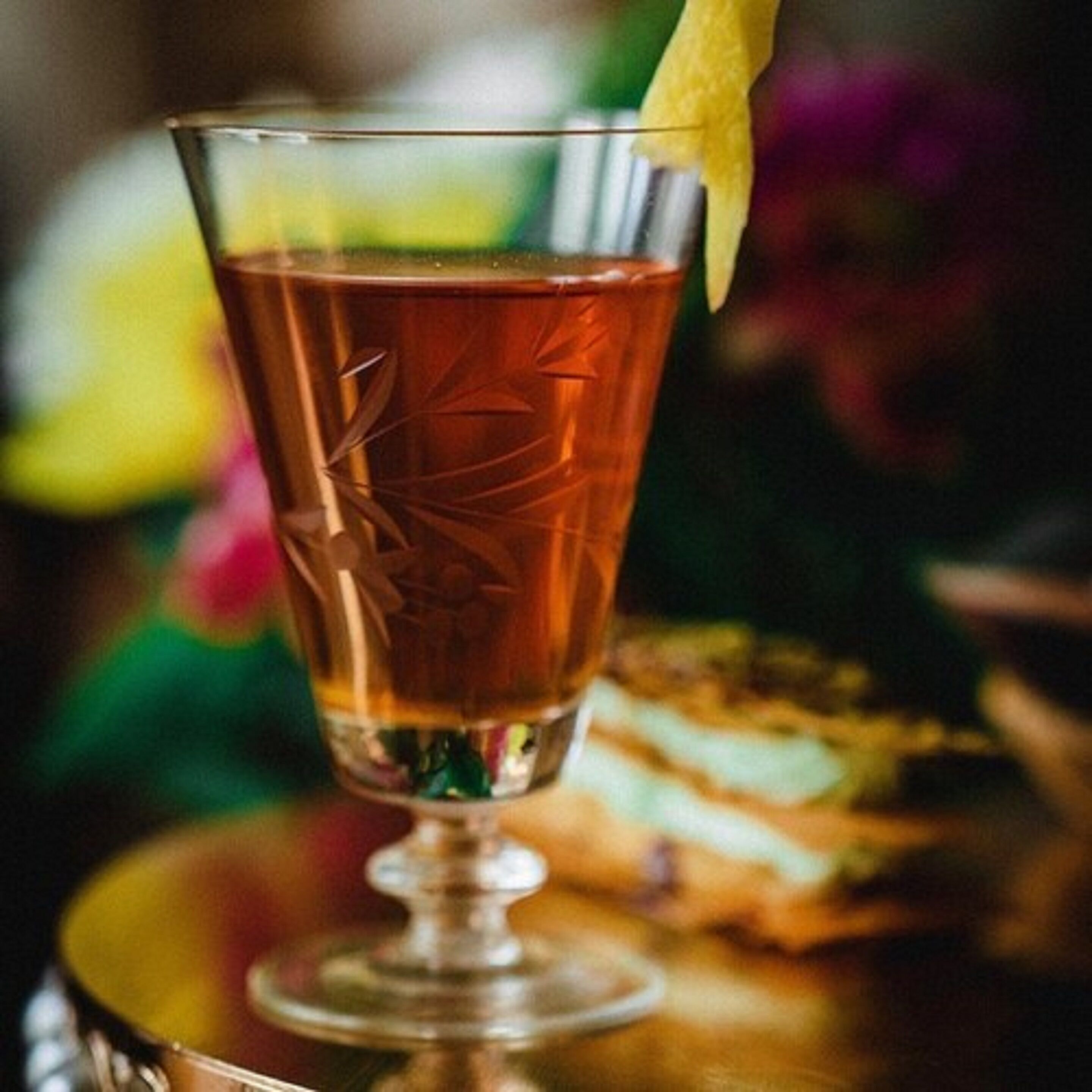 A glass with a drink, possibly a cocktail, on a table.