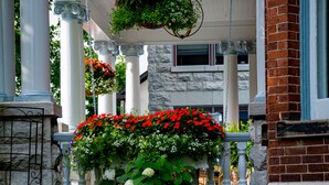 Une véranda couverte ornée de suspensions fleuries, un mur en pierre et une petite cascade.