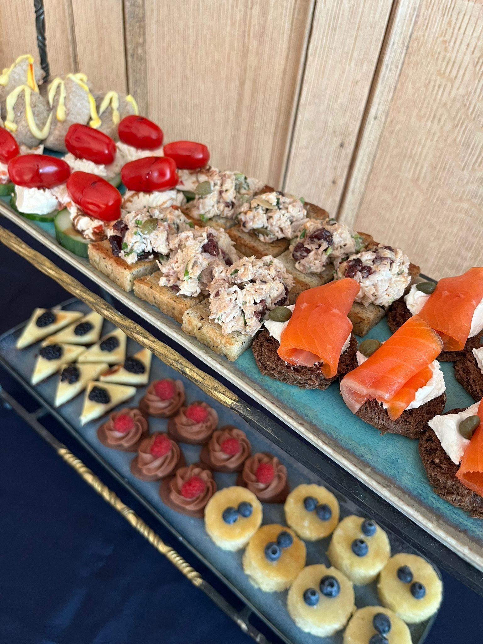 A variety of appetizers on a tray, including smoked salmon, cream cheese, and various garnishes.