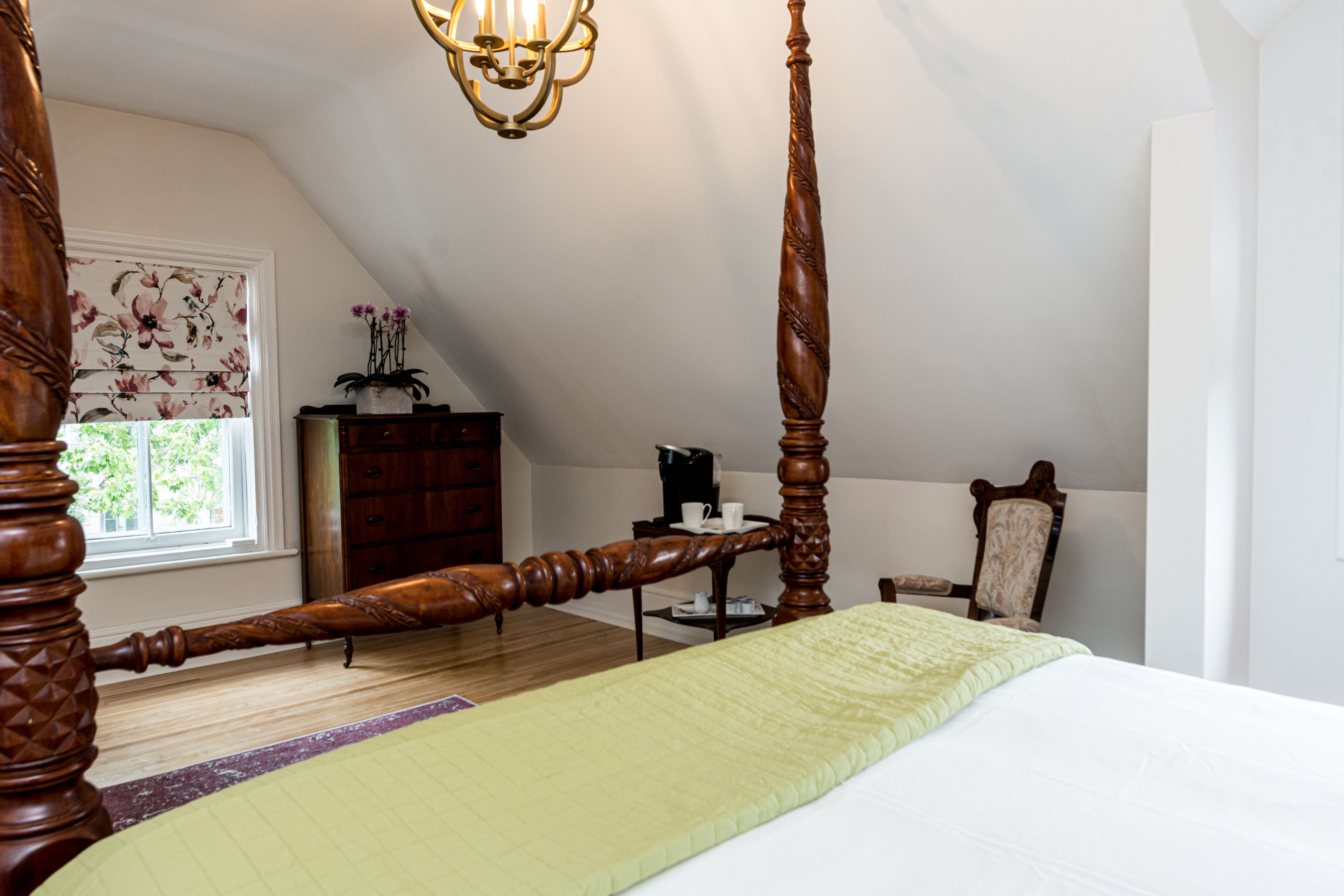 Une chambre à coucher avec un lit à baldaquin, un lustre, une commode en bois et une chaise.