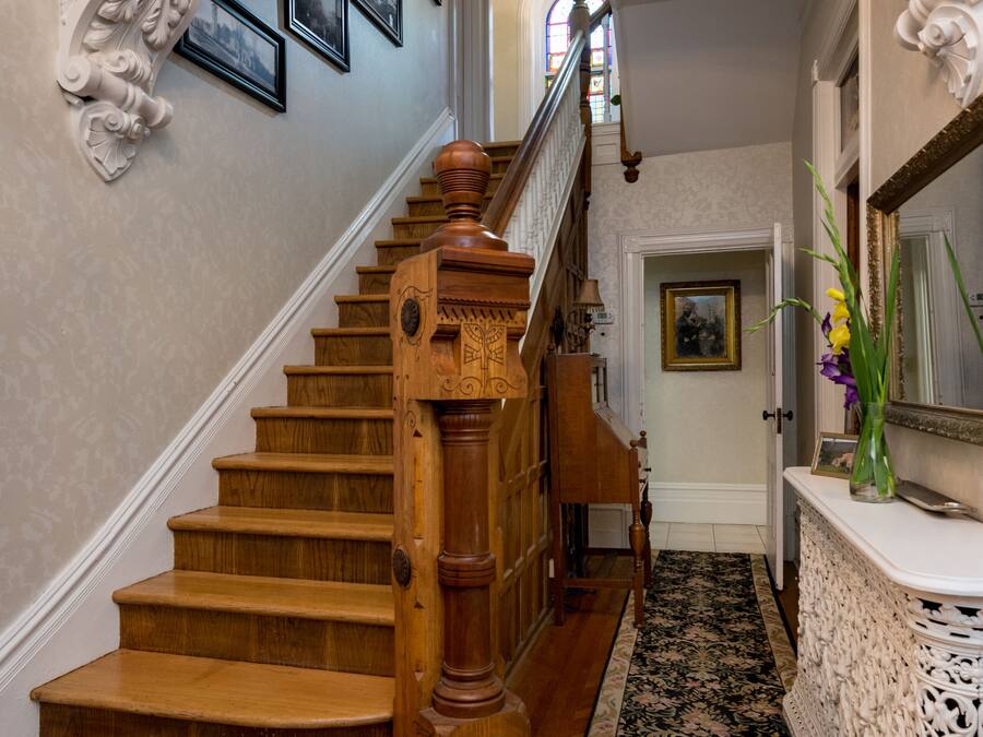 A grand staircase with ornate woodwork and a black and white patterned carpet.