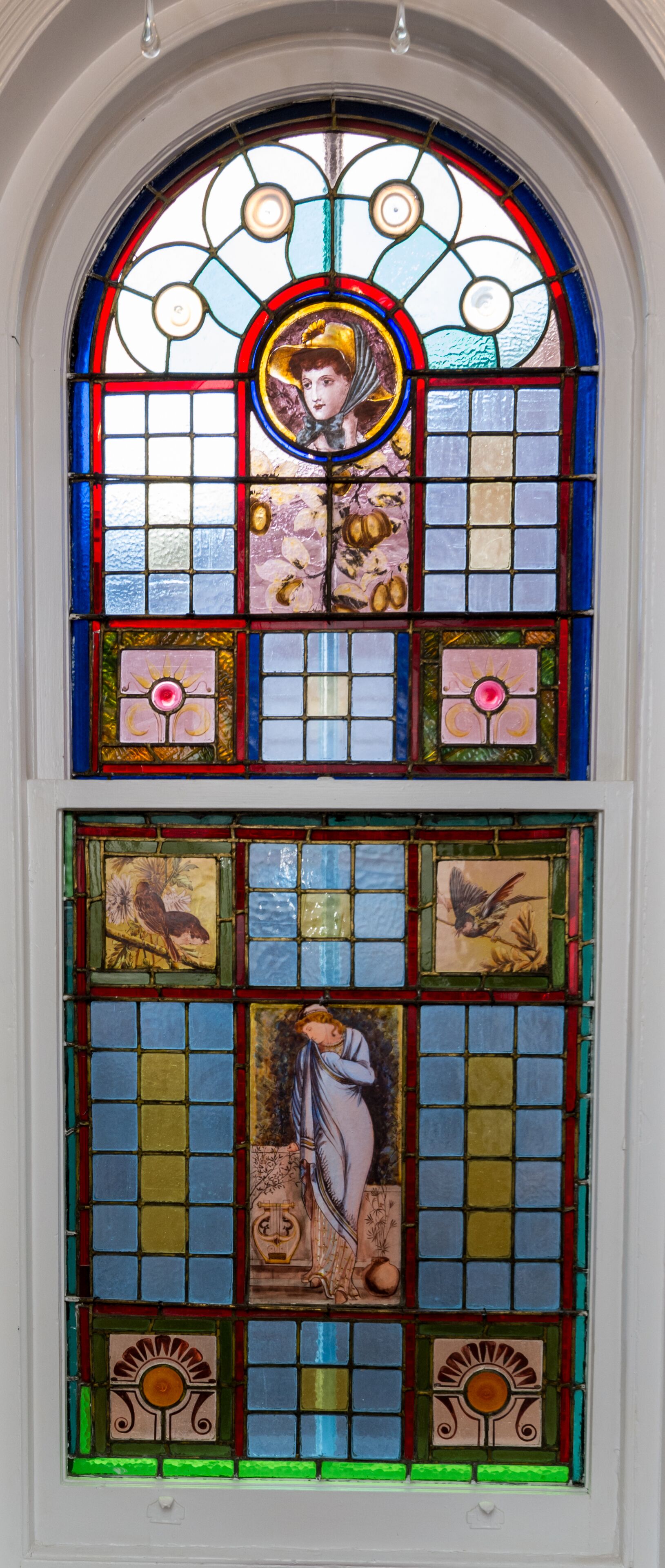 A stained glass window with religious figures and floral designs.
