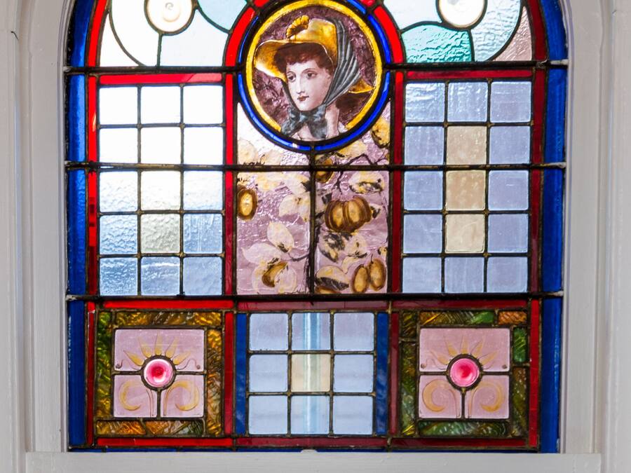 A stained glass window with religious figures and floral designs.