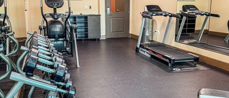 Une salle de sport équipée de tapis de course, d’haltères et d’appareils d’exercice.
