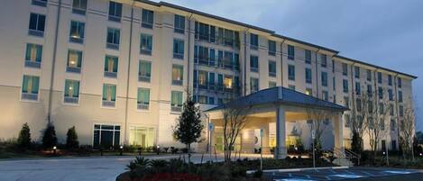 A multi-story hotel with a covered entrance and a parking lot.