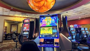 A casino with multiple slot machines, a high-limit table area, and a large, ornate chandelier. - Boomtown Casino & Hotel New Orleans (Harvey)