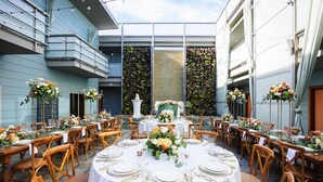 An outdoor dining area with round tables set for a meal, surrounded by wooden chairs. - Shade Hotel (Manhattan Beach)
