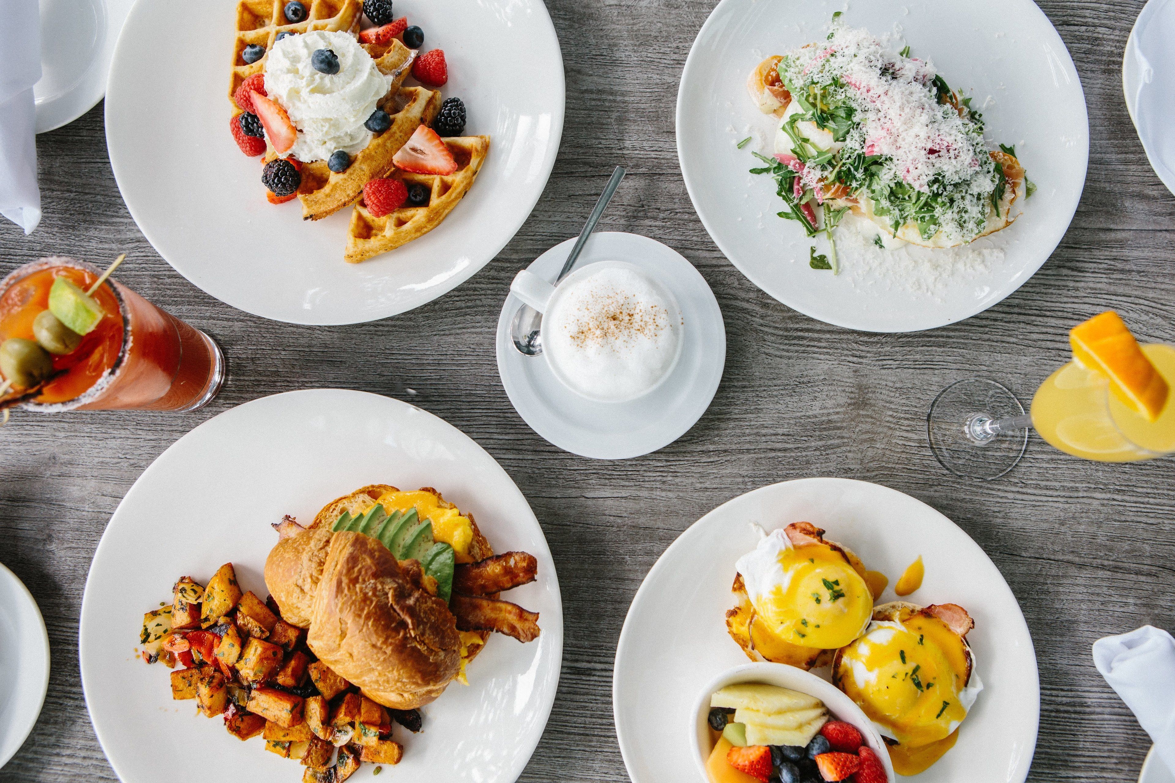 A breakfast buffet with waffles, scrambled eggs, and various fruits.