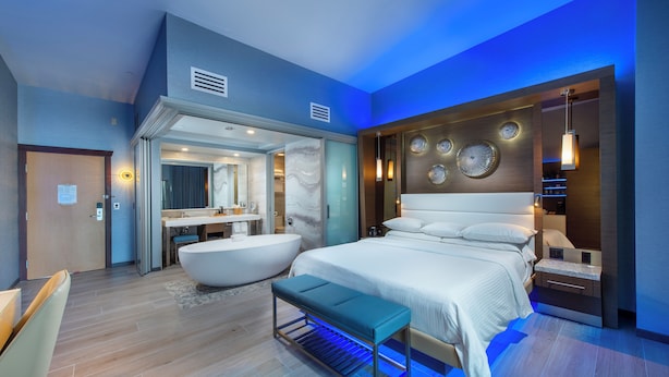 A modern bedroom with a large bed, a bathtub, and a vanity with a mirror. - Shade Hotel (Manhattan Beach)