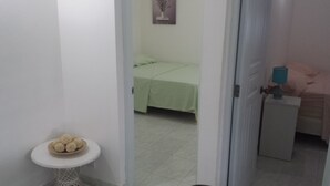 Quarto com cama, uma mesinha com um prato de comida e uma mesa de cabeceira com abajur.