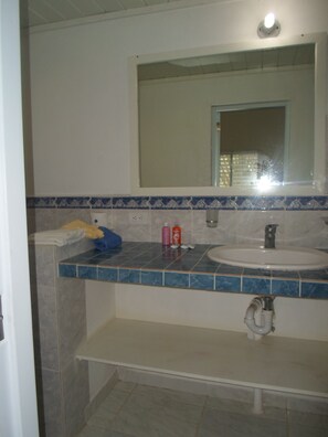 A bathroom with a sink, mirror, and tiled backsplash. - Casita Playa Coson (Las Terrenas)