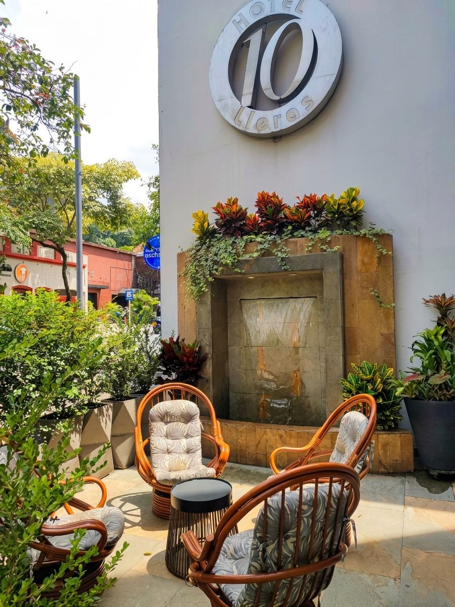A hotel entrance with a large sign, outdoor seating, and a decorative wall.