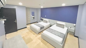 A modern hotel room with two beds, a dark door, a small bathroom, and a large window. - Hotel Lleras 10 (Medellín)