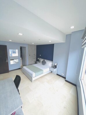 A modern bedroom with a bed, bedside tables, a desk, and a chair. - Hotel Lleras 10 (Medellín)