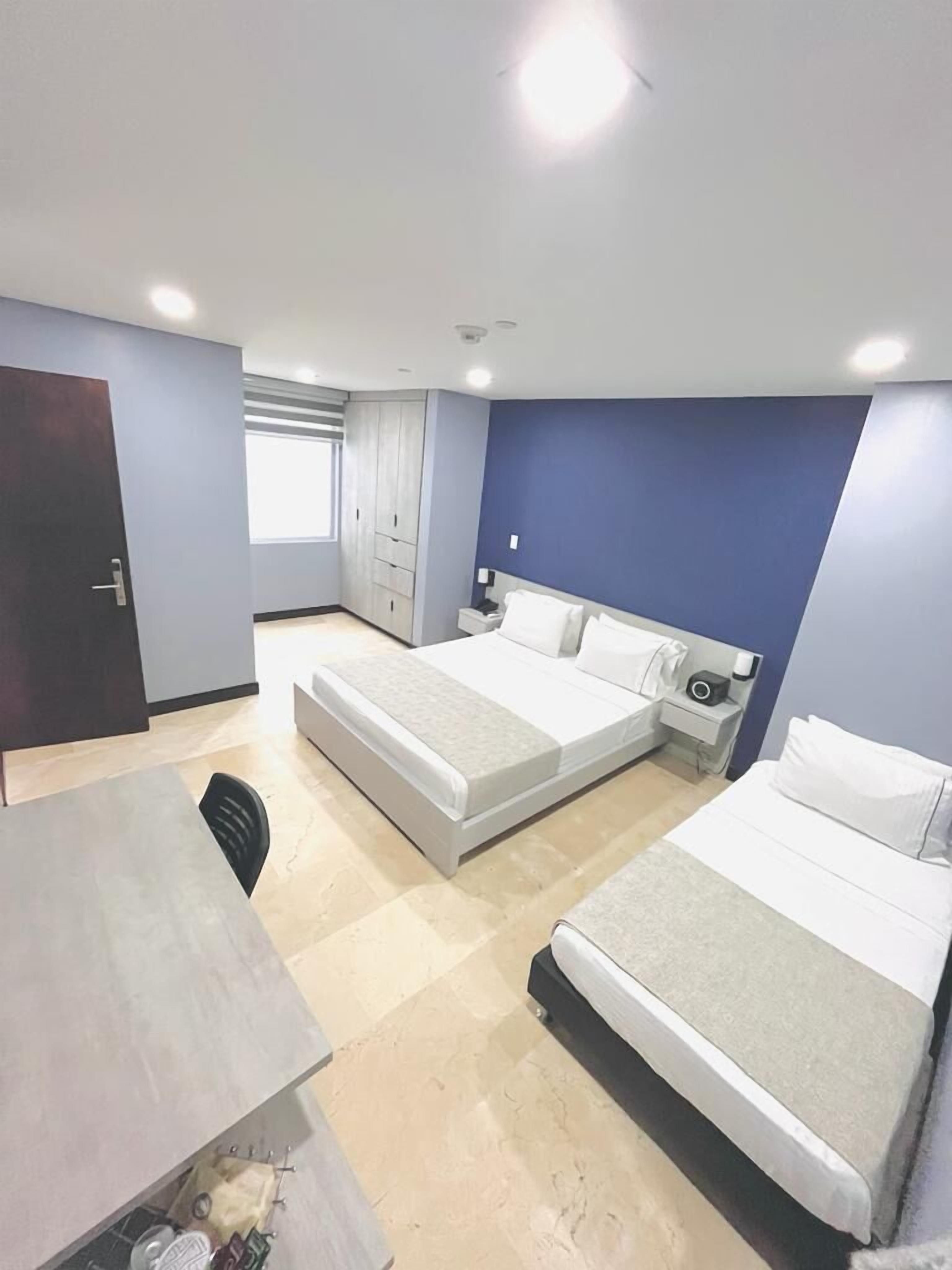 A hotel room with two beds, a desk, and a wardrobe.