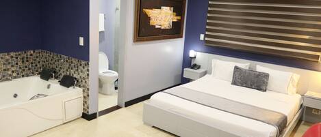 Una habitación de hotel moderna con una cama grande, un baño separado con bañera y vistas a la ciudad por la ventana.