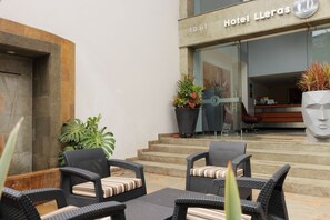 A hotel entrance with outdoor seating and potted plants. - Hotel Lleras 10 (Medellín)