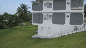 Un edificio de dos pisos con un letrero que dice Paradise Inn, que presenta una escalera y vistas de la vegetación circundante.