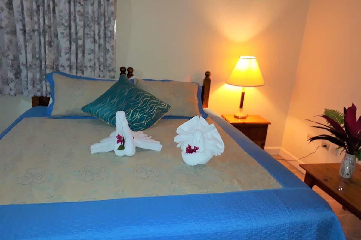 Une chambre d’hôtel avec un lit bien fait, une lampe de chevet et une plante sur la table de chevet.