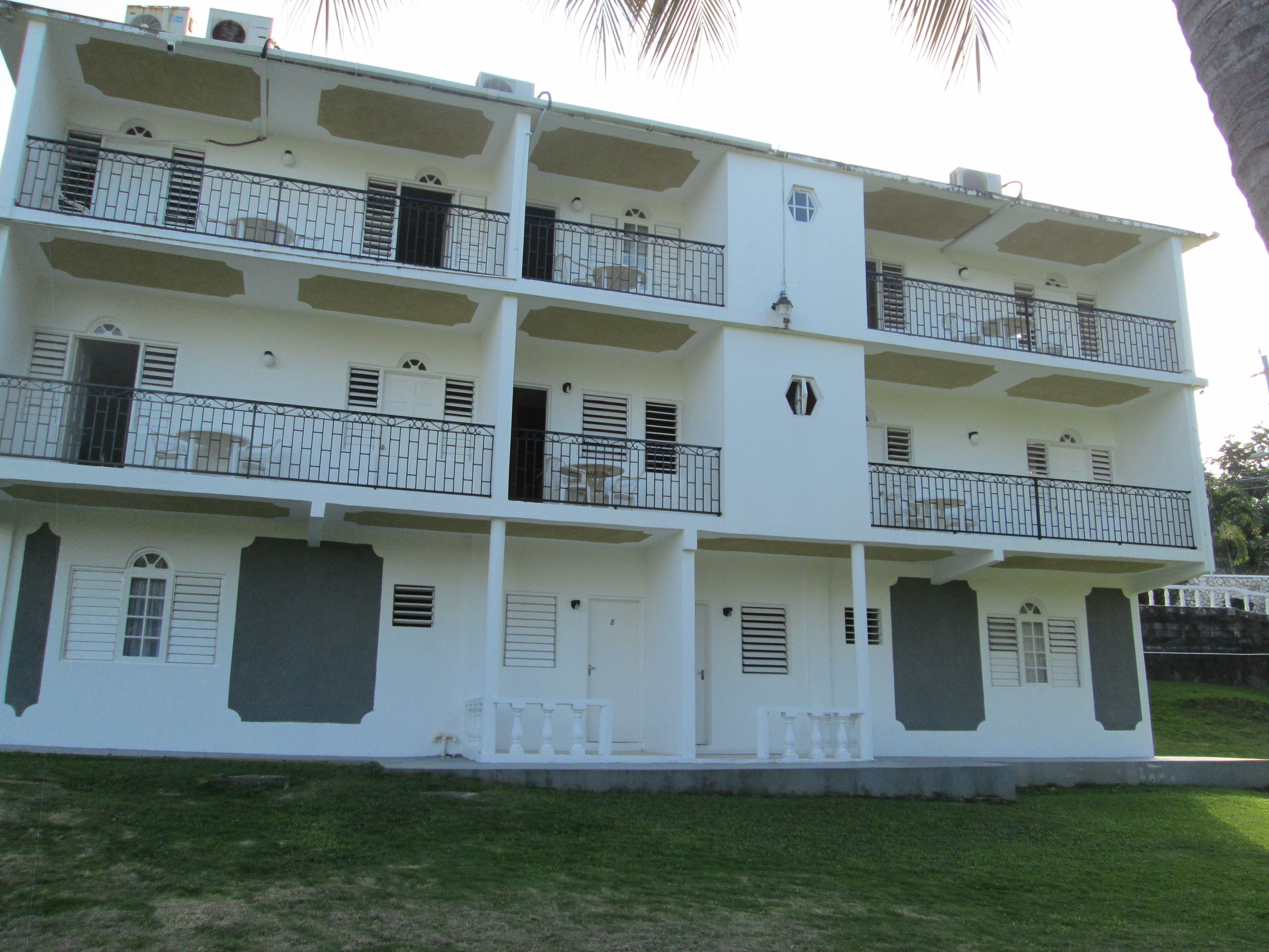 Un edificio de varios pisos con balcones, ventanas con contraventanas y un techo plano.