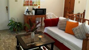 Una sala de estar acogedora con un sofá, una mesa de centro, un escritorio con computadora y un televisor.
